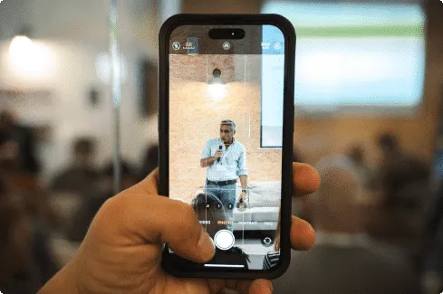 A participant filming a speaker pitching on stage